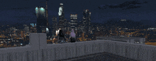 two people sitting on a ledge looking at a city skyline at night