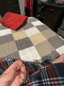 a person laying on a bed with a plaid blanket on top