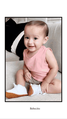 a baby in a pink tank top is sitting on the floor