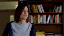 a woman is standing in front of a bookshelf with books on it