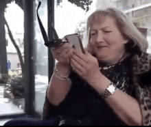 an older woman is holding a pair of sunglasses and looking at her phone .