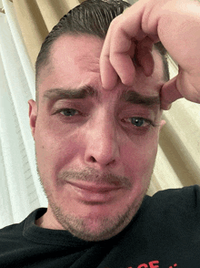 a man with a beard wearing a black shirt that says ' peace ' on it is crying