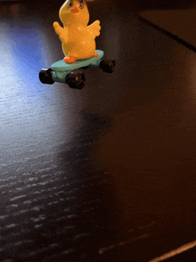 a toy duck riding a blue skateboard on a table