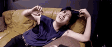 a man is laying on a couch laughing while holding his hair .