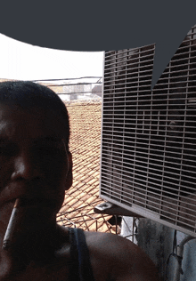 a man smoking a cigarette next to a fan