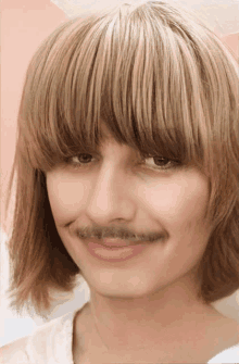 a woman with fringe and a fake mustache smiles for the camera