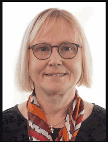 a woman wearing glasses and a scarf looks at the camera