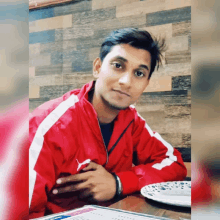 a man in a red puma jacket sits at a table with a menu in front of him