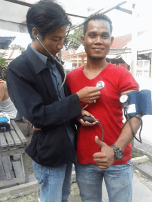 a man in a red shirt is getting his blood pressure taken