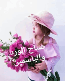 a little girl wearing a pink hat is holding a bouquet of flowers .