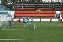 a soccer game is being played in front of a stadium that has the word sport on it