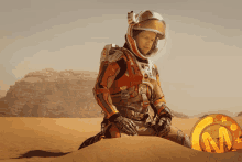 a man in a space suit sits on a pile of sand next to a gold coin with the letter m on it