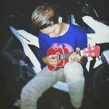 a young man is playing a guitar in front of a honda motorcycle