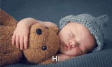 a baby sleeping with a teddy bear that says hi on the bottom