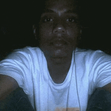 a man wearing headphones and a white shirt is taking a selfie in the dark .