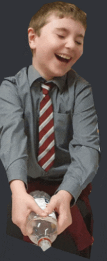 a boy in a gray shirt and red and white striped tie is holding a plastic bottle