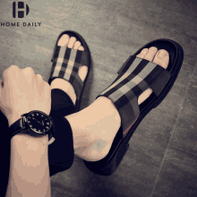 a person wearing sandals and a watch with the word home daily on the bottom