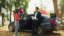 a man and a woman standing in front of a car with a license plate that says mh - rr - 738