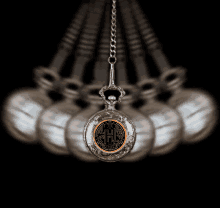 a pocket watch with the letter h on it is hanging from a chain