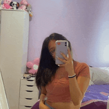 a woman is taking a picture of herself in a mirror with her phone .