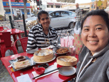 two women are sitting at a table with plates of food in front of a store that says subway clinic