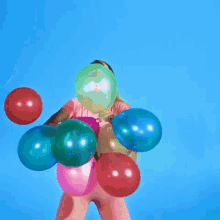 a woman is holding a bunch of colorful balloons in her hand .