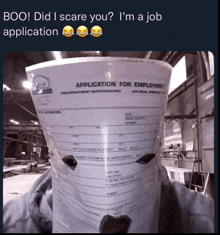 a person is holding a bucket with an application for employment on it in front of their face