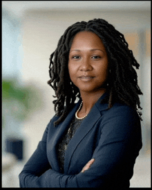 a woman with dreadlocks wearing a blue jacket and pearls