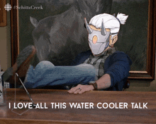 a man sitting at a desk with a mask on his face and the words i love all this water cooler talk below him