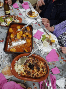 a group of people are sitting at a table with plates of food