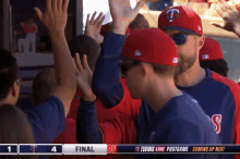 a group of baseball players giving each other a high five in front of a scoreboard that says coming up next