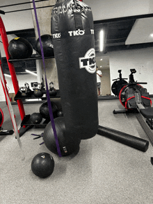 a black tk punching bag is sitting on the floor in a gym