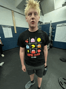 a boy wearing a game over t-shirt is standing in a gym