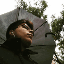 a man wearing glasses and ear buds is holding an umbrella