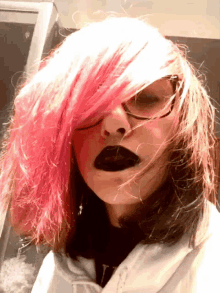 a girl with pink hair and black lips is wearing a white hoodie