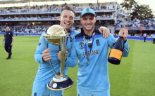 two england players holding a trophy and a bottle