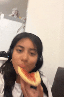 a woman wearing headphones is eating a piece of pizza