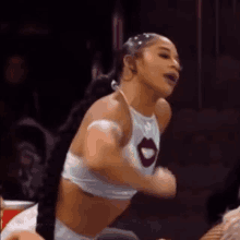 a woman in a white crop top with a red lip is dancing in a ring .