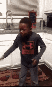 a young boy is dancing in a kitchen in front of a sink and a window
