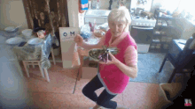 a woman in a pink vest is holding a bowl of food in front of a sign that says om