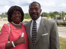 a man and woman are posing for a picture in front of a street