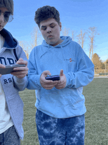 a boy wearing a sweatshirt that says rs is looking at a cell phone