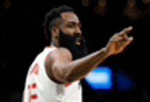 a basketball player with a beard is pointing at something in the air .