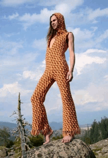 a man standing on a rock wearing an orange and brown jumpsuit