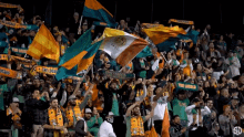 a crowd of people in a stadium holding flags and a scarf that says ' the locals ' on it