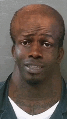 a man with a very long neck and a tattoo on his neck is looking at the camera .