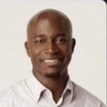 a bald man is smiling for the camera while wearing a striped shirt .