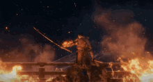 a man holding a sword is standing on a bridge over a fire