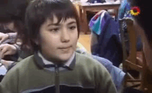 a young boy is making a funny face in a classroom with other children .