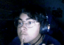 a person wearing headphones and eating noodles in a dark room